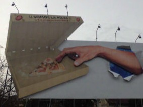 Estructura publicitaria creativa en forma de caja de pizza, con una mano interactuando para simular la apertura, diseñada para campañas de alto impacto.